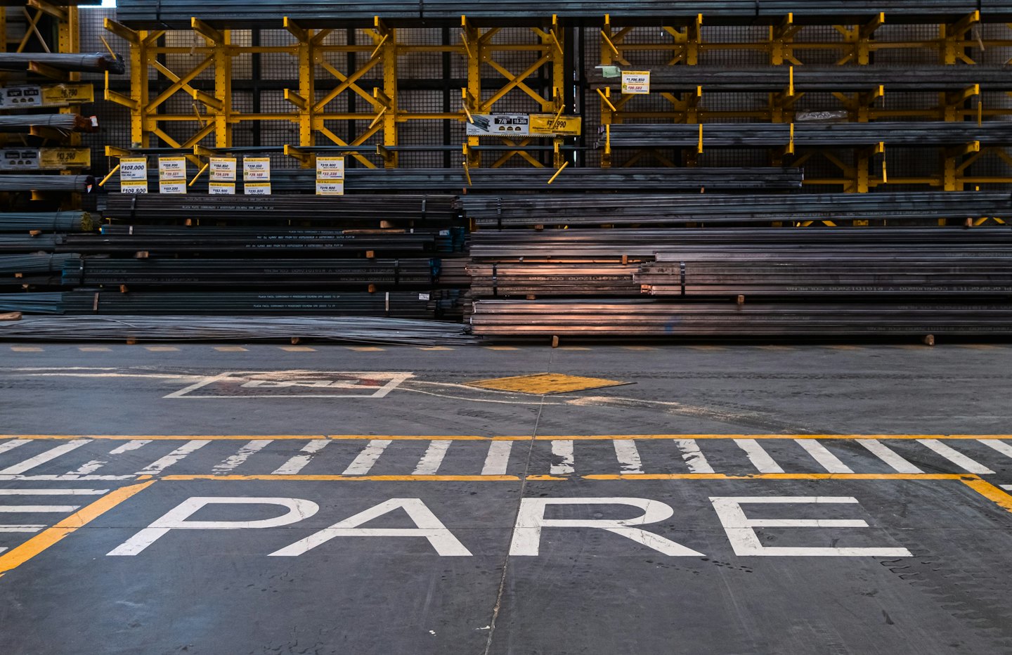 Reihen von Metallstangen und Rohren auf gelben Industrieregalen.